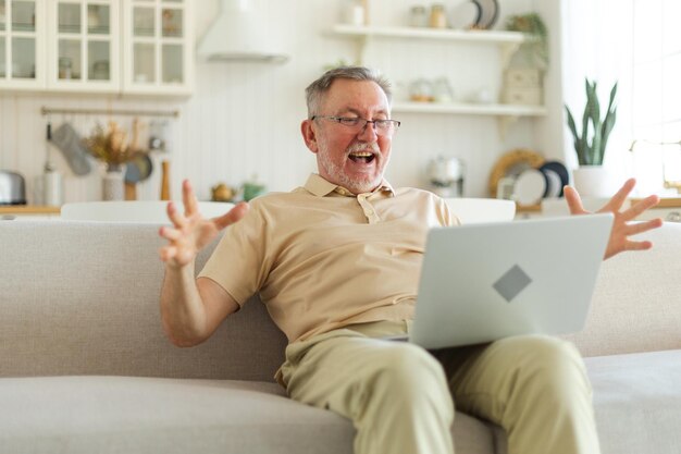 Aufgeregt älterer Mann mittleren Alters, euphorischer Sieger, älterer reifer Großvater, der auf den Laptop blickt und gr. liest