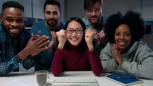Aufgeregt blickt ein multiethnisches Team auf den Computerbildschirm und applaudiert dem Erfolg