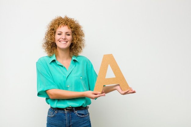 aufgeregt, glücklich, freudig, den Buchstaben A des Alphabets haltend, um ein Wort oder einen Satz zu bilden.