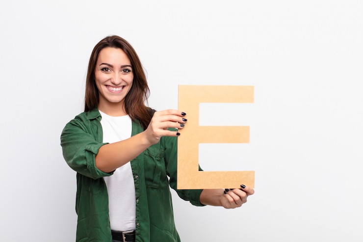 Foto aufgeregt, glücklich, freudig, den buchstaben e des alphabets haltend, um ein wort oder einen satz zu bilden.