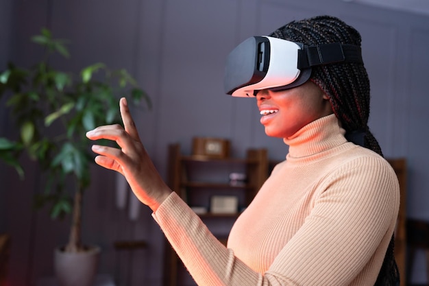 Aufgeregte Afro-Frau genießt das Einkaufen in der virtuellen Realität und hebt die Hand mit leicht geöffnetem Mund