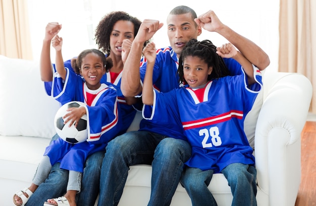 Aufgeregte afroamerikanische Familie, die ein Fußballspiel aufpasst