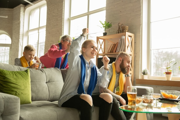 Aufgeregte familie, die zu hause ein fußballspiel guckt großeltern, eltern und kind