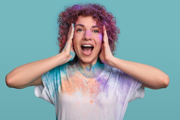 Aufgeregte Frau in Holi-Farben im Studio