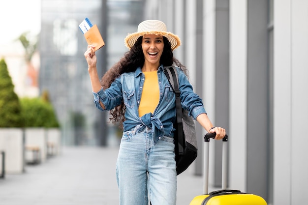 Aufgeregte junge Frau, die allein in den Urlaub geht und einen Pass zeigt