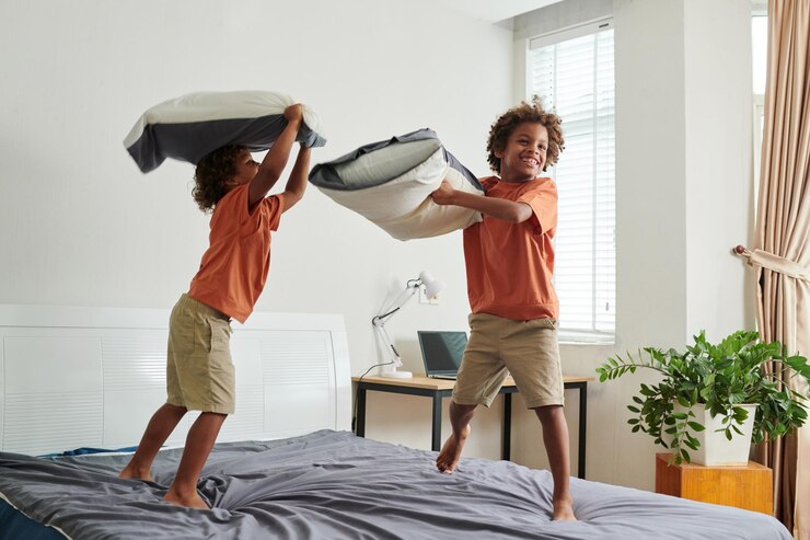 Foto aufgeregte kinder springen und kämpfen mit kissen auf einem großen bett