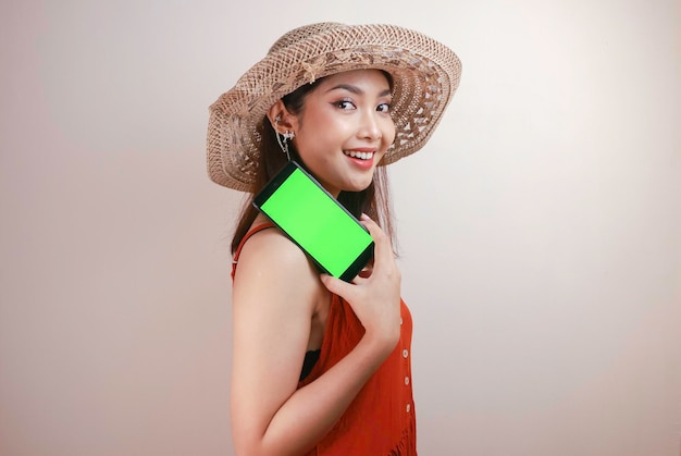 Aufgeregte und lächelnde junge Asiatin, die einen grünen Bildschirm auf dem Smartphone in ihrer Hand zeigt