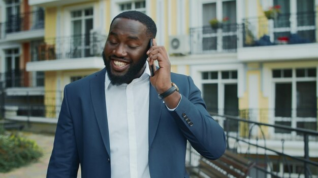 Aufgeregter afrikanischer Geschäftsmann ruft draußen an. Afro-Mann spricht mit Smartphone