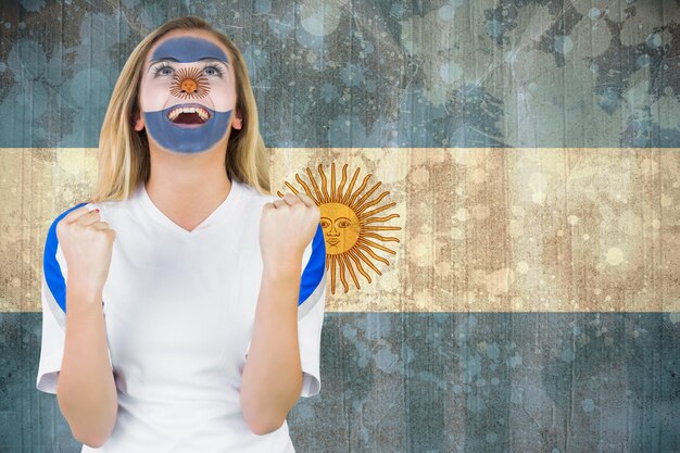 Foto aufgeregter argentinischer fan in gesichtsbemalung jubelt gegen argentinische flagge mit grunge-effekt