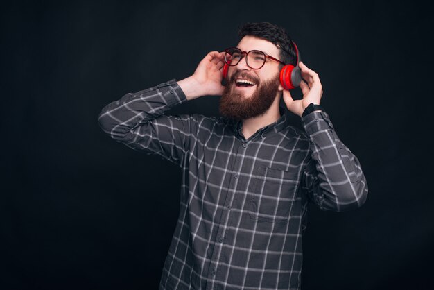 Aufgeregter bärtiger Mann singt, während er die Musik über ein rotes Headset hört.