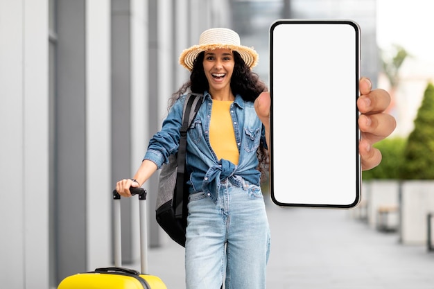 Aufgeregter hübscher Damenreisender, der Smartphonemodell zeigt