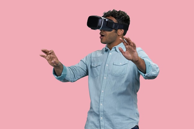 Aufgeregter indischer Mann erlebt den braunen Südasiaten der virtuellen Realität isoliert auf rosa Hintergrund