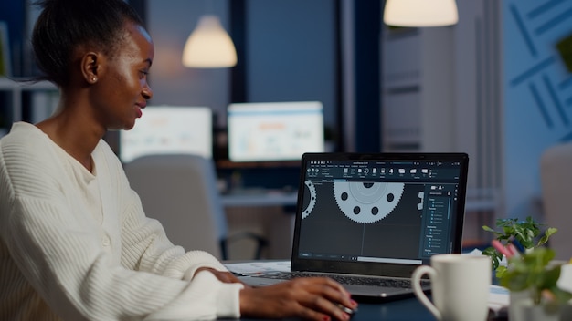 Aufgeregter Industriearchitekt der schwarzen Frau, der an modernen CAD-Programmüberstunden arbeitet und im Start-up-Büro sitzt. Wirtschaftsingenieur, der die Idee eines Prototyps auf dem PC studiert, der CAD-Software auf dem Gerätedisplay zeigt