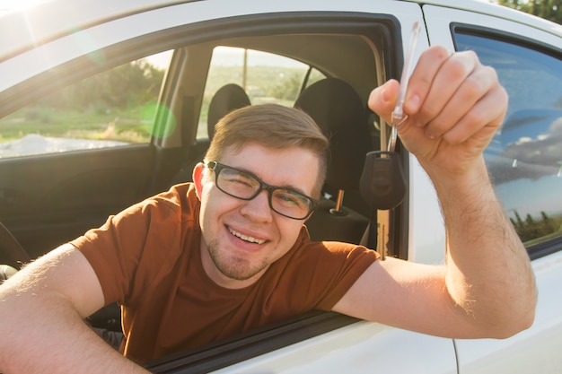 Foto aufgeregter junger mann, der einen autoschlüssel in seinem neuen fahrzeug zeigt.