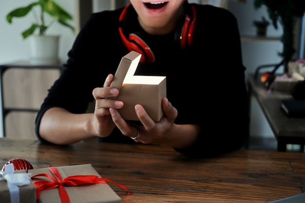 Aufgeregter junger Mann, der Weihnachtsgeschenkbox öffnet.