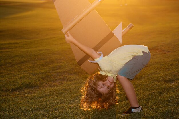 Aufgeregter Kinderjunge träumt und reist Junge mit Flugzeugspielzeug im Freien Glückliches Kind, das mit Spielzeugluft spielt