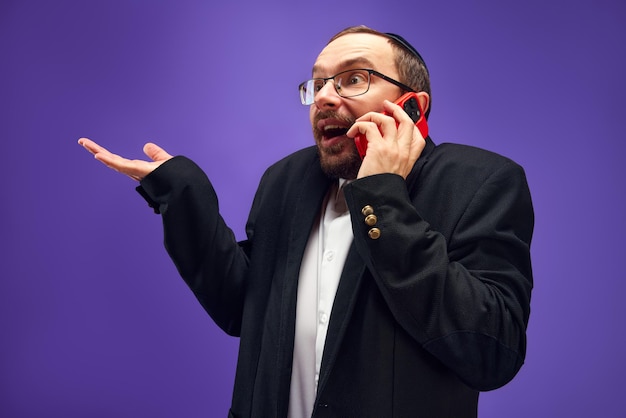 Aufgeregter Mann in Brille und Yarmulke emotional telefonieren Begrüßung mit Feiertag gegen