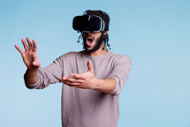 Aufgeregter Mann mit VR-Brille erkundet die virtuelle Realität und berührt Objekte im Metaversum. Person, die ein tragbares Headset verwendet und ein Videospiel spielt, während sie mit den Händen Gesten macht