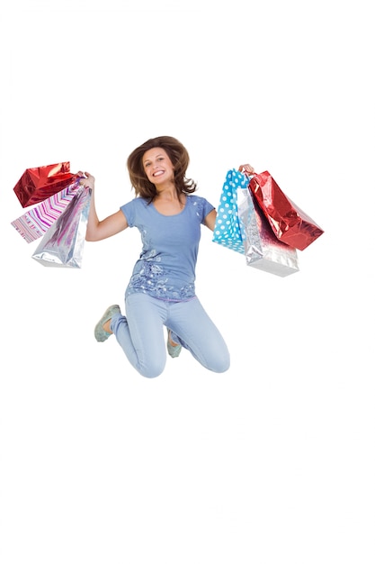 Aufgeregter springender Brunette beim Halten von Einkaufstaschen