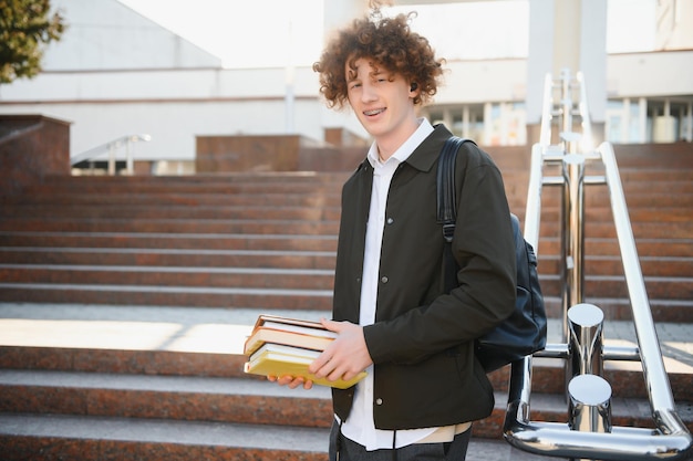 Aufgeregter Student, der eine Pause zwischen den Klassen in der Nähe der Universität hat und im Freien in die Kamera lächelt