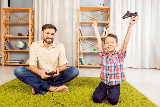 Aufgeregter Vater und Sohn spielen Videospiele. glücklicher kleiner Junge gewinnt