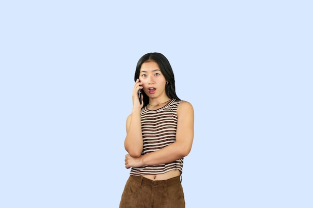 Aufgeregtes asiatisches Studentenmädchen gibt eine Hand-Fa-Geste der Traurigkeit wow glücklich in blauem Hintergrund