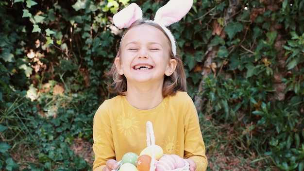 Foto aufgeregtes gefühl überraschung kind mädchen in kaninchenohren kaninchenkostüm halten korb osterfarbige eier