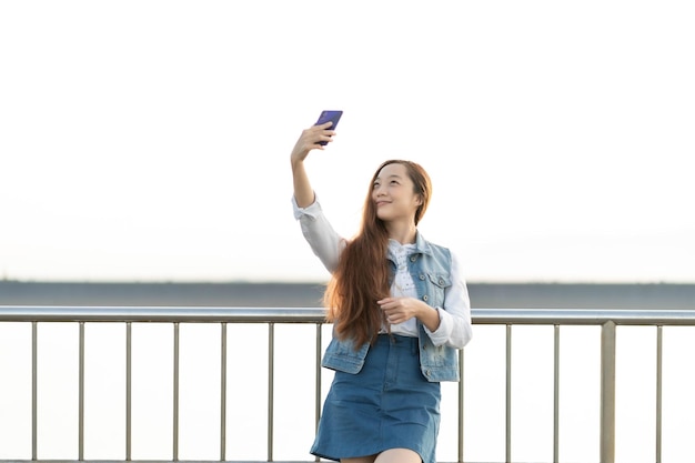 Aufgeregtes junges Mädchen, das ein Selfie macht, während es an der Brücke steht