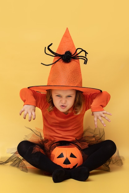 Aufgeregtes Kind Kürbis HalloweenMakes Boo Grimassen Gesicht emotionale Mädchen Pose isoliert mit Süßigkeiten Eimer