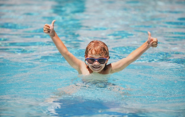 Aufgeregtes Kind mit Sonnenbrille im Pool am Sommertag Kind im Schwimmbad