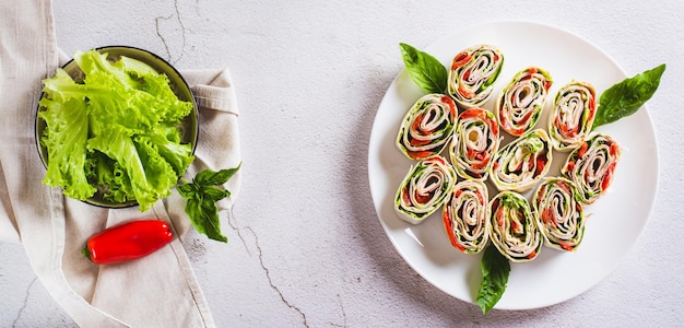 Aufgerollte Sandwiches mit Salatspeck und gebackenen Paprikaschoten in einem Webbanner mit Tortilla-Draufsicht