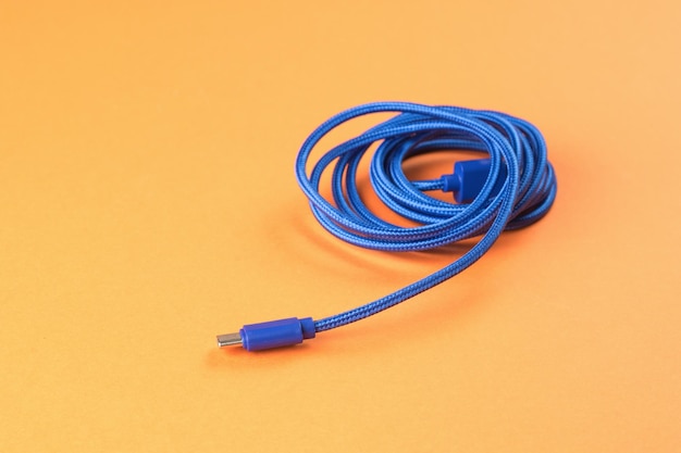 Aufgerolltes blaues USB-Kabel auf orangefarbenem Hintergrund