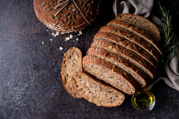 Foto aufgeschnittenes sauerteigbrot aus vollkornmehl und kürbiskerne auf einem gitter mit olivenöl und schwarzer olive