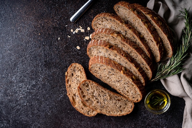 Foto aufgeschnittenes sauerteigbrot aus vollkornmehl und kürbiskerne auf einem gitter mit olivenöl und schwarzer olive