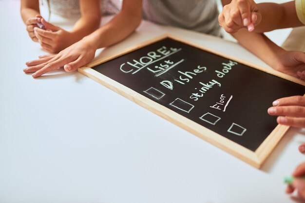 Auflisten ihrer Aufgaben Nahaufnahme von Kindern, die zu Hause eine Liste mit Aufgaben an eine Tafel schreiben