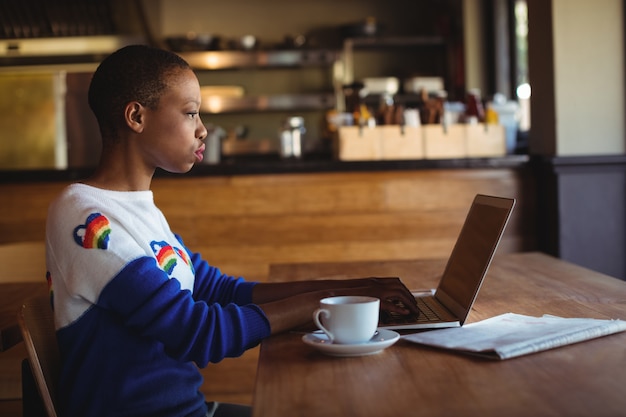 Aufmerksame Frau mit Laptop beim Kaffee