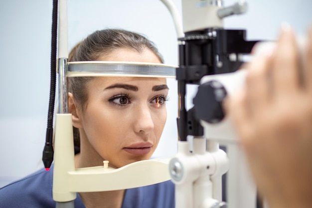 Aufmerksamer Optometrist untersucht Patientin an Spaltlampe in Augenklinik Junge schöne Frau wird mit Augendruck auf spezielle ophthalmologische Geräte diagnostiziert