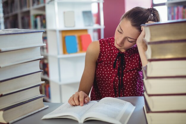 Aufmerksames Schulmädchen, das in der Bibliothek studiert