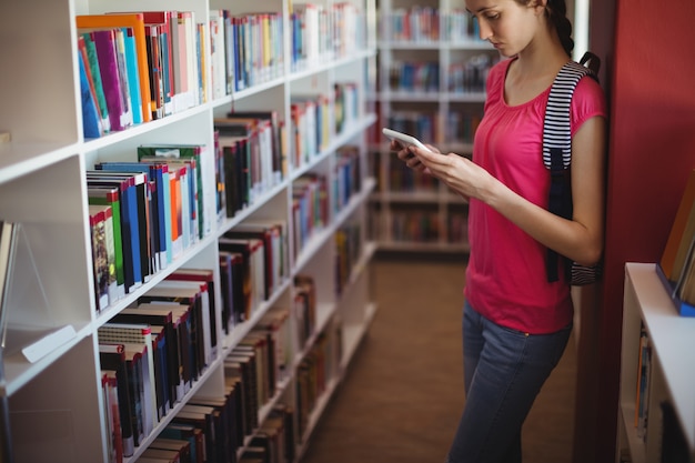 Aufmerksames Schulmädchen mit digitalem Tablet in der Bibliothek