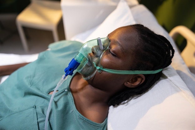 Aufnahme einer afrikanischen Frau im Krankenhaus mit offenen Augen, die eine Sauerstoffmaske trägt und die Augen schließt