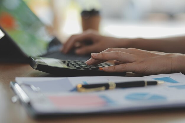 Aufnahme einer asiatischen jungen Geschäftsfrau, die an ihrem Laptop an ihrem Arbeitsplatz arbeitet