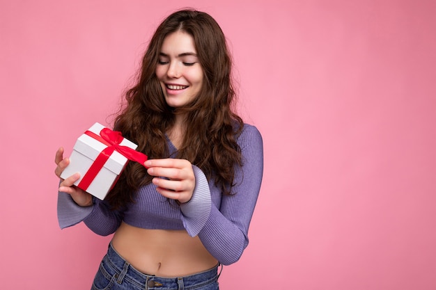 Aufnahme einer attraktiven, positiv lächelnden jungen brünetten Frau, die über bunter Hintergrundwand isoliert ist?