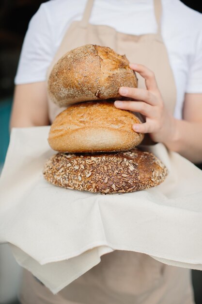 Aufnahme einer fröhlichen Bäckerin, die in die Kamera lächelt, die in der Nähe der Vitrine steht Bäckerin oder Verkäuferin in ihrer Bäckerei, die frisches Brotgebäck und Backwaren verkauft