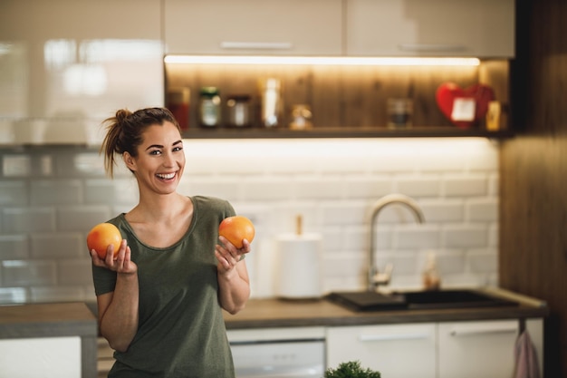 Aufnahme einer glücklichen jungen Frau, die zu Hause in ihrer Küche ein Obstfrühstück zubereitet.