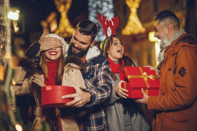 Aufnahme einer Gruppe fröhlicher junger Freunde mit Weihnachtsgeschenken, die sich beim Ausgehen vergnügen.
