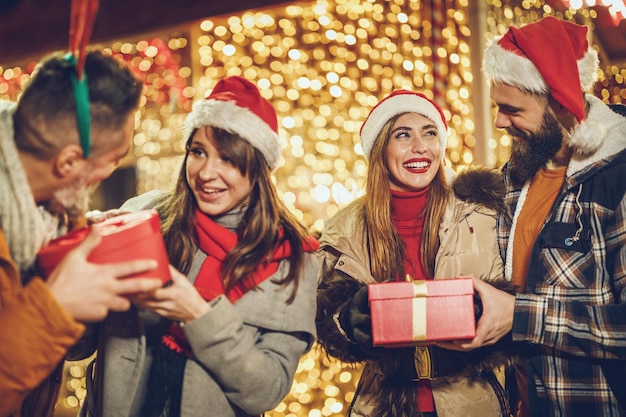 Aufnahme einer Gruppe fröhlicher junger Freunde mit Weihnachtsgeschenken, die sich beim Ausgehen vergnügen.