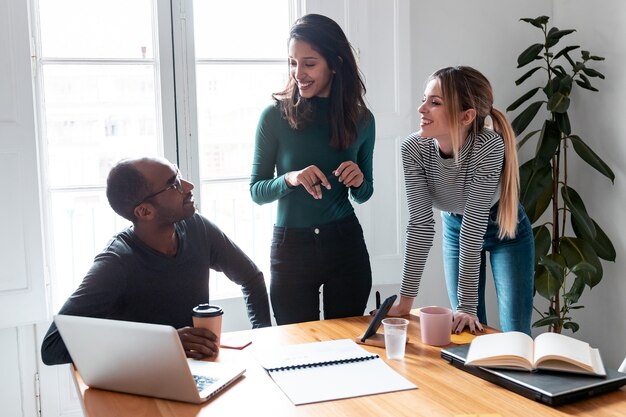 Aufnahme einer hübschen jungen Unternehmerin, die seinen Kollegen am Coworking-Platz ein Projekt erklärt.