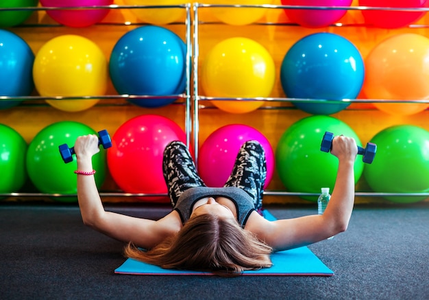 Aufnahme einer jungen Frau, die im Fitnessstudio mit Hanteln trainiert?