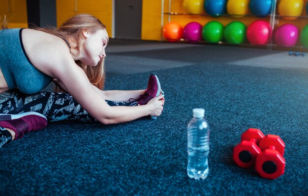 Aufnahme einer jungen Frau, die sich im Fitnessstudio streckt