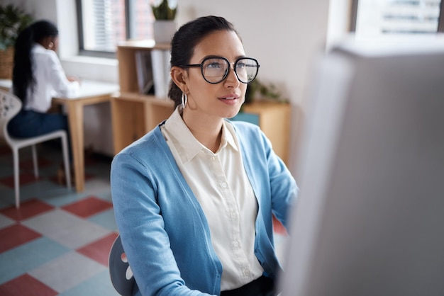 Aufnahme einer jungen Geschäftsfrau, die einen Computer an ihrem Schreibtisch in einem modernen Büro benutzt